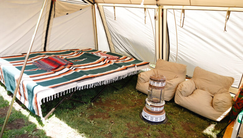テントの中は、コットを3つ並べてそれに大判のブランケットをかけてベッドに。パーフェクションストーブの750型石油ストーブは暖房としてだけでなく、発光することから夜はランタンのように使っている。