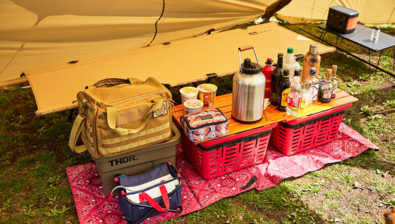 ホームセンターで購入したバスケットにD.I.Y.の天板を乗せドリンクコーナーを設置。トミーヒルフィガーのケースは、ゴルフ用のカートバッグを折り畳みチェアに付けて小物入れに転用。