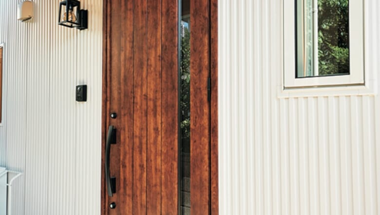 建物横に配置した玄関は、扉を一部ガラスにすることで室内側にも光が差し込む。「少し柔らかさを出したくて、木目調のデザインにして、ウッドデッキとのつながりも意識しています」。