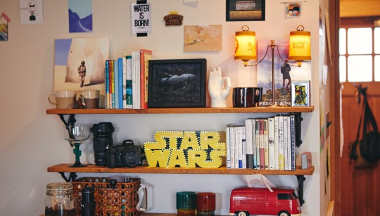 ダイニングの自作したディスプレイ棚には、山関連の本やカルマストアのシャンデリアホルダーなどが並ぶ。