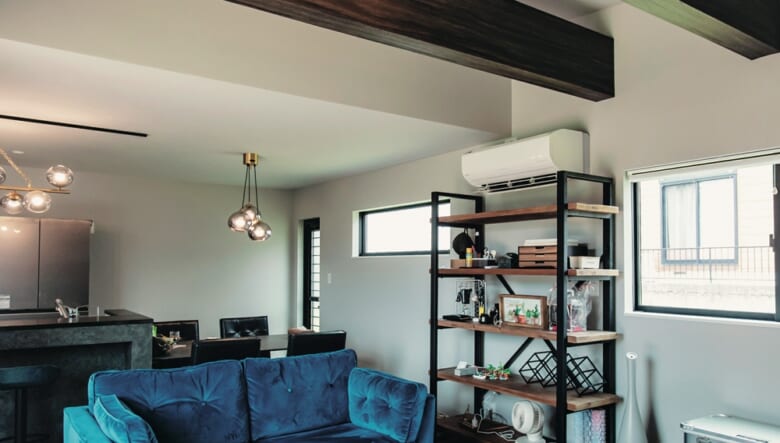 リビングは折り上げ天井にすることで、空間を広く見せつつ、梁を見せて視覚的にもアクセントに。中央に置いたソファの脚とテーブルの脚を、梁の色味と合わせたことで統一感が生まれた。雰囲気バツグンなブルーのソファと隣のラックは、ともにダルトンのもの。