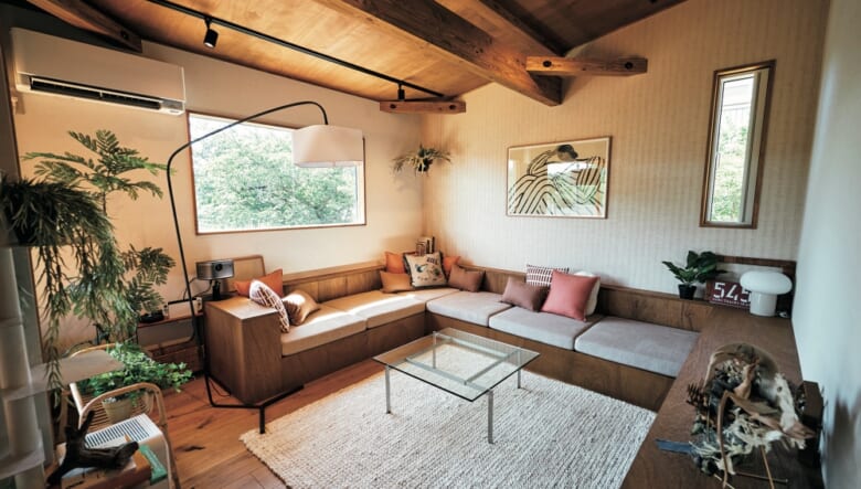 角のリビングには、テーブルを囲うようにピッタリ設置されたソファと収納棚を設置。こちらは、この家のデザインとアレンジを担当したEIGHT DESIGNが設計したワンオフの家具。ソファの座面の下はすべて収納になっている。ガラステーブルは、デンマークのブランド、フリッツ・ハンセンのリプロダクトモデル、PK61。テレビの代わりにプロジェクターを白壁に投影して、映画やゲームを楽しんでいる。