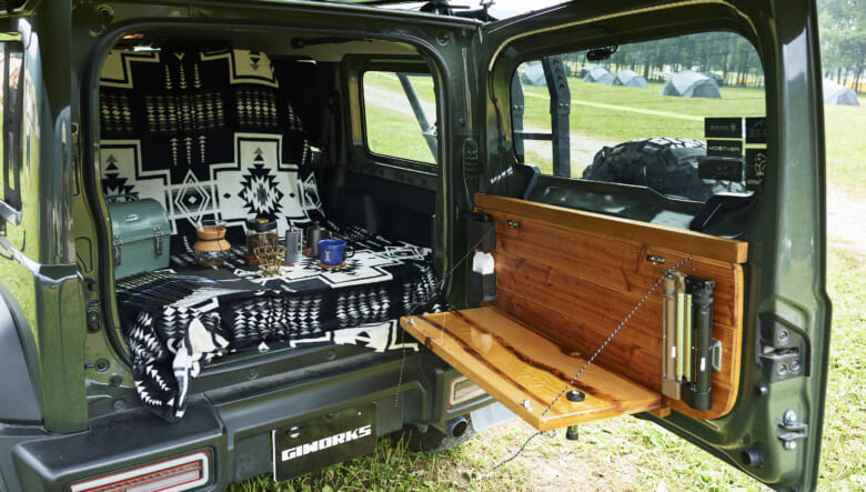 クルマの荷室も活用。バックドアの内側にはウッドのパネルを取り付け、収納式のサイドテーブルが付く。ここをキッチンなどのスペースとしても使えそう。