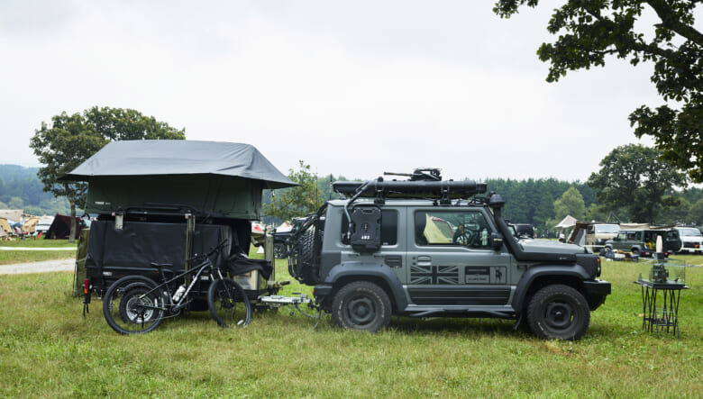 ジムニー シエラが牽引しているのは、アメリカのトレーラをジムニーサイズにカスタムした唯一無二のモデル。フォグランプやシュノーケルを付け、軍用車のような佇まいも目を引く。