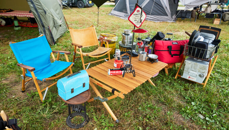 タープ下に設けたリビングには、ノラズテーブルを設置した横並びスタイル。カーミットチェアはそれぞれナチュラルマウンテンモンキーのマイスターシートとオールドマウンテンのレザーに座面を張り替え。