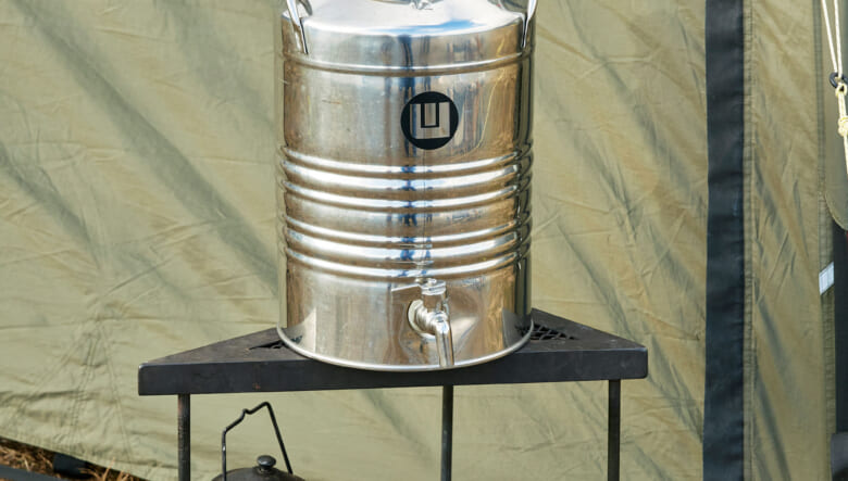 ジャグ台にしたアイアン製の三角テーブルは、ケンさんの自作。薪バサミや火かき棒など鉄製ギアもすべて自作だ。