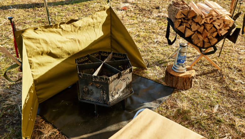 焚き火スペースの前に設置した風防は、タキビズムのマルチロングペグで設置。奥に見える薪ラックはハイランダー。