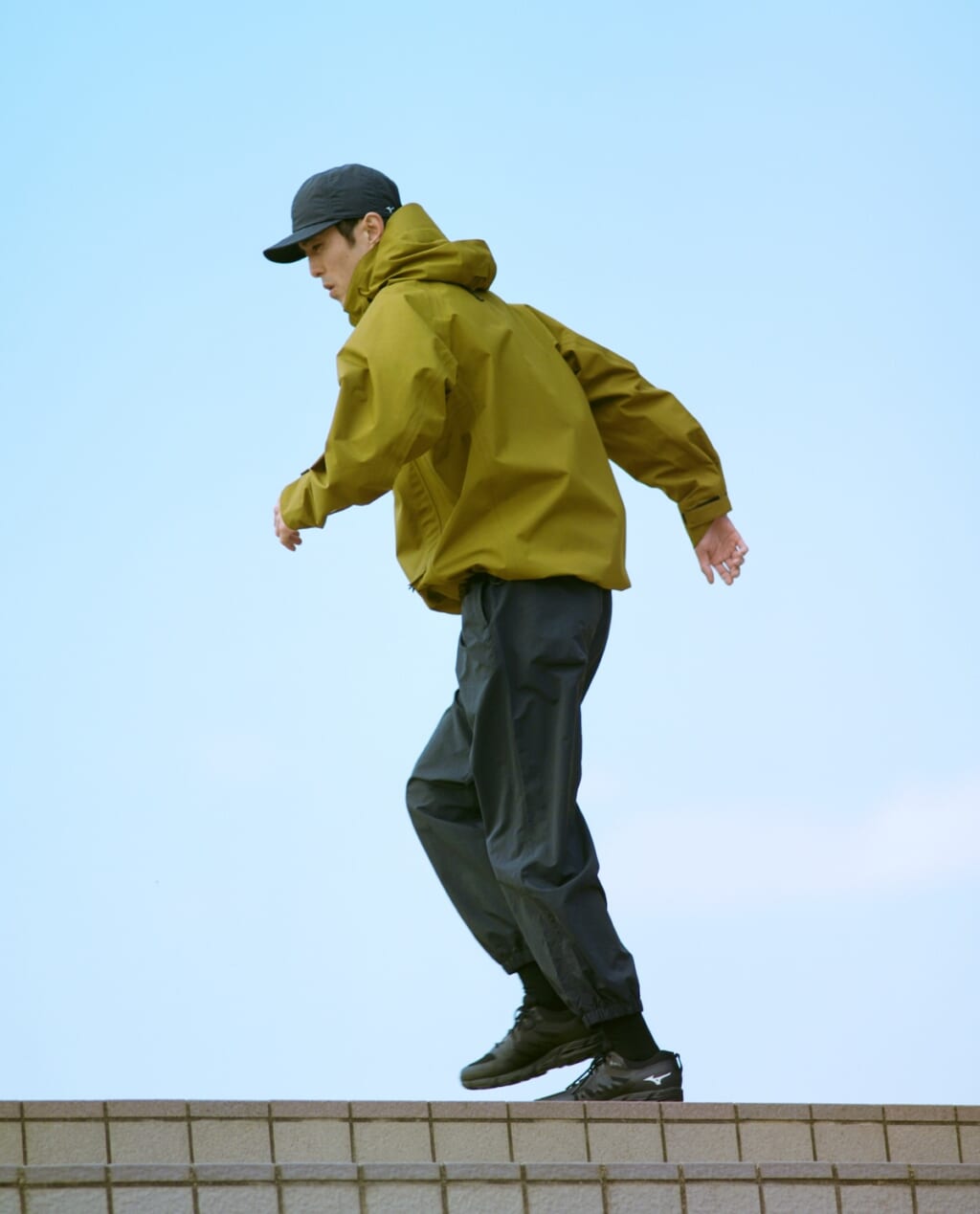 ミズノとマーガレット・ハウエルのコラボアイテムと着用した男性モデル。着用アイテム：WATER REPELENT NYLON POPLIN CAP、Gore-Tex RECYCLED POLYESTER POPLIN COAT