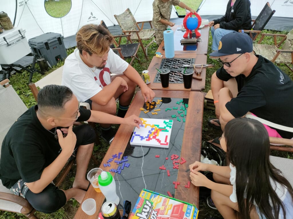 大人と一緒にテントサイトでボードゲームを楽しんでいる様子