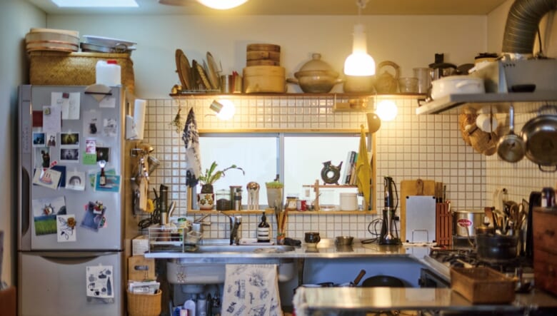 .ジブン好みにリフォームしたキッチンには毎日立っているという勝さん。足元から天井まで料理道具が隙間なく並び、料理家の自宅さながら。頭上の棚はお手製で、左奥には彩光のための天窓がある。