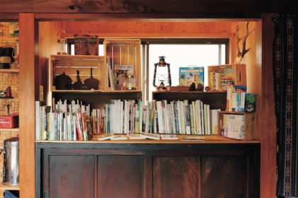 野遊びにまつわる書籍が並ぶ本棚。「個人的に勉強したい内容の本や、お客さんに読んでほしい本を置いています」。本棚の下には天然木で作られた大きな看板を設置。